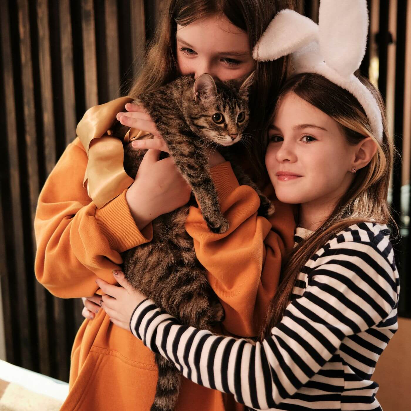 Zwei kleine Mädchen halten ihre Katze in den Armen und lächeln dabei