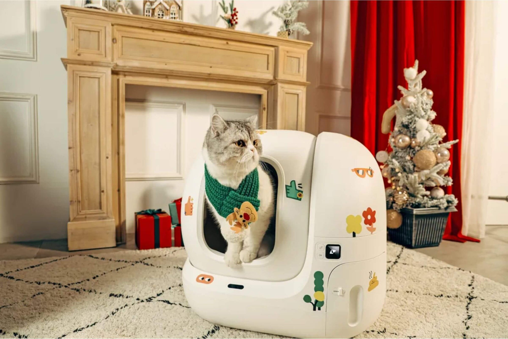 Weiße Katze sitzt in einem automatischem Katzenklo und die Umgebung ist weihnachtlich dekoriert